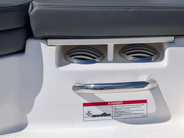 Slide: The Image of Close-up of a boat seat with gray upholstery, cup holders, and a warning label. - 14