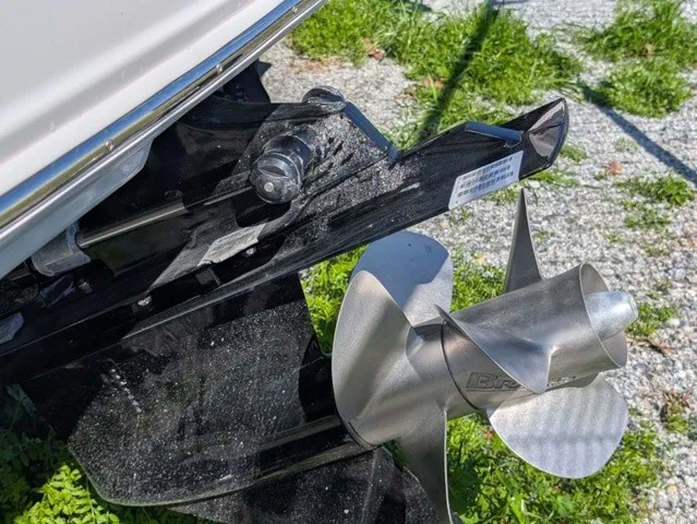 Slide: The Image of Close-up of a shiny propeller on a Chaparral 23 SSi boat, surrounded by grass and gravel. - 13