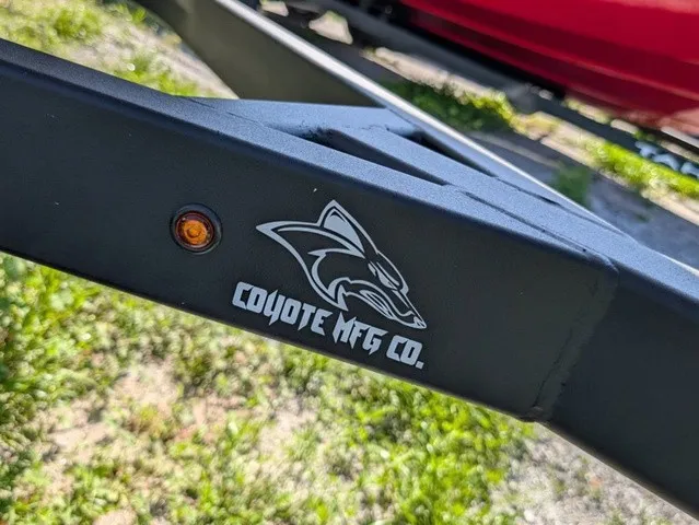 Slide: The Image of A black boat trailer by Coyote MFG Co. with an orange light, standing on grass. - 5