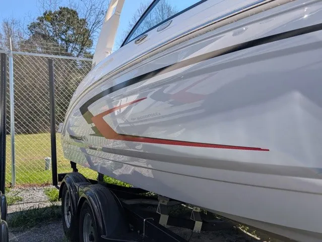 Slide: The Image of A 2026 Chaparral 23 SSi boat on a trailer next to a chain-link fence. - 7
