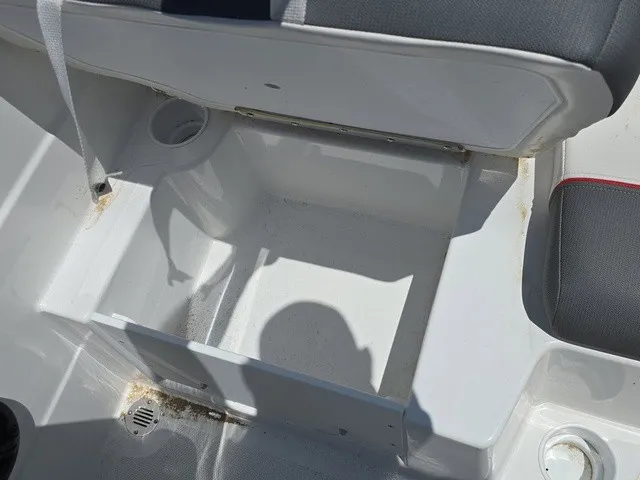 Slide: The Image of An open storage compartment on a boat with gray upholstery and a cup holder. - 27