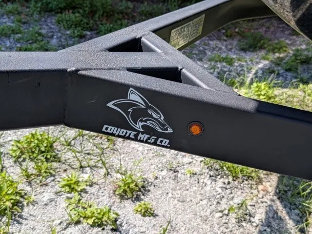 Slide: The Image of A black boat trailer with the Coyote Mfg Co. logo is on a gravel surface. - 4