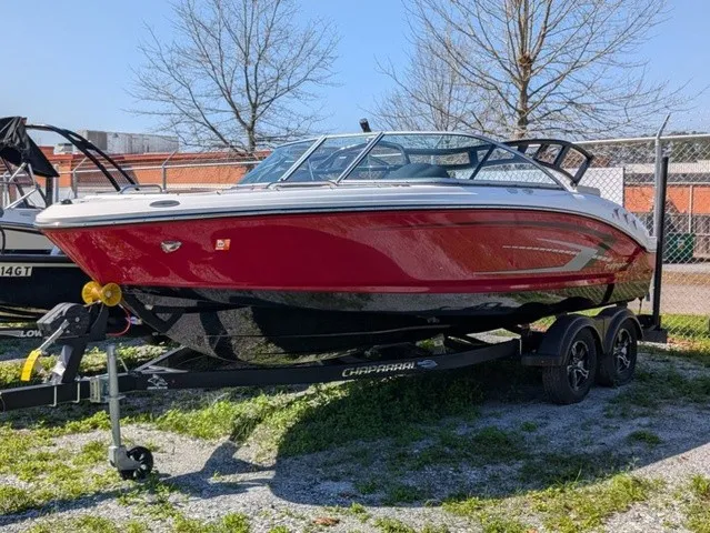 Slide: The Image of A red 2023 Chaparral 21 SSi boat on a trailer, parked on grassy ground. - 2
