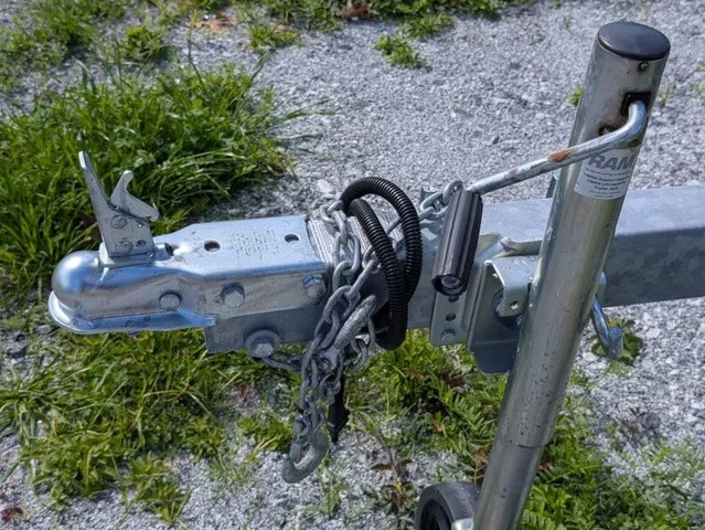 Slide: The Image of Close-up of a boat trailer hitch with chains and safety pin on gravel ground. - 4