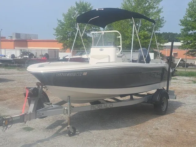 Slide: The Image of A 2016 Robalo R160 Center Console boat on a trailer, featuring a black Bimini top. - 2