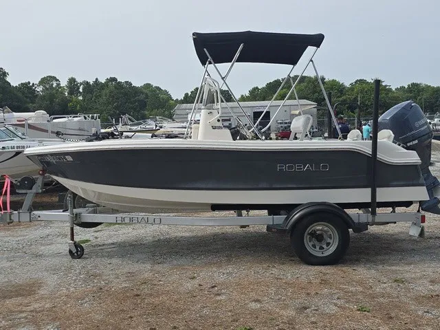 Slide: The Image of A 2016 Robalo R160 Center Console boat on a trailer, featuring a black Bimini top. - 9