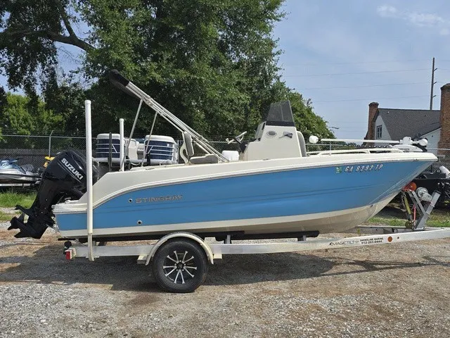 Slide: The Image of A blue and white 2023 Stingray 173 CC boat on a trailer, surrounded by trees and other boats. - 7