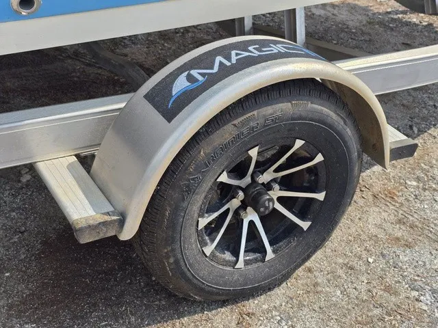 Slide: The Image of A boat trailer with a black wheel and a silver fender displaying "MAGIC." - 12