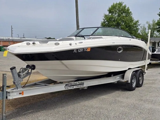Slide: The Image of A 2022 NauticStar 243 DC boat on a trailer, parked on a gravel lot. - 2