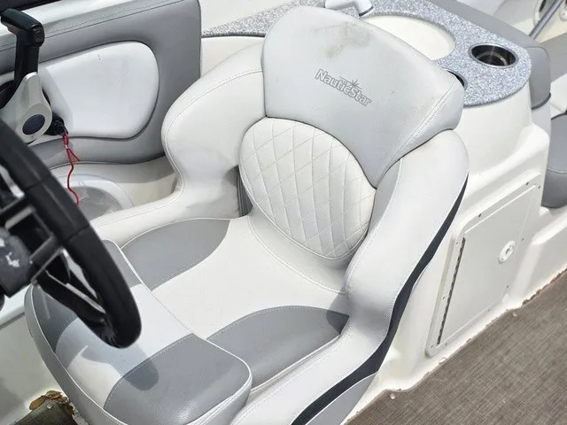 Slide: The Image of The 2022 NauticStar 243 DC features a luxurious, cushioned captain's chair with gray and white accents. - 14