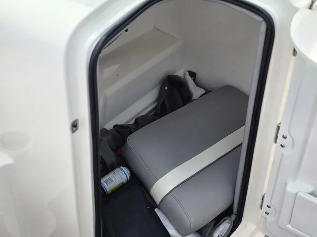 Slide: The Image of A small storage area with a gray seat cushion and some items inside. - 20