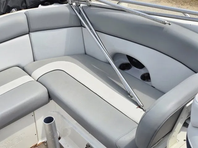 Slide: The Image of The 2022 NauticStar 243 DC features gray and white upholstery with built-in cup holders. - 16