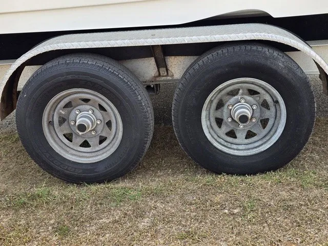 Slide: The Image of A tandem axle trailer with two large tires on grass. - 10
