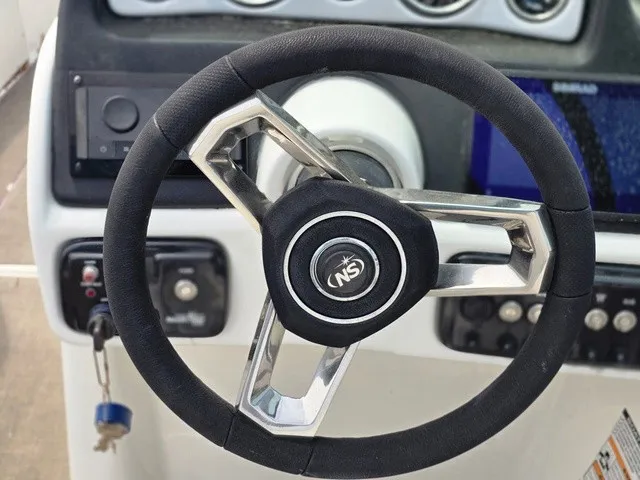 Slide: The Image of The image shows the steering wheel of a 2022 NauticStar 243 DC boat. - 27