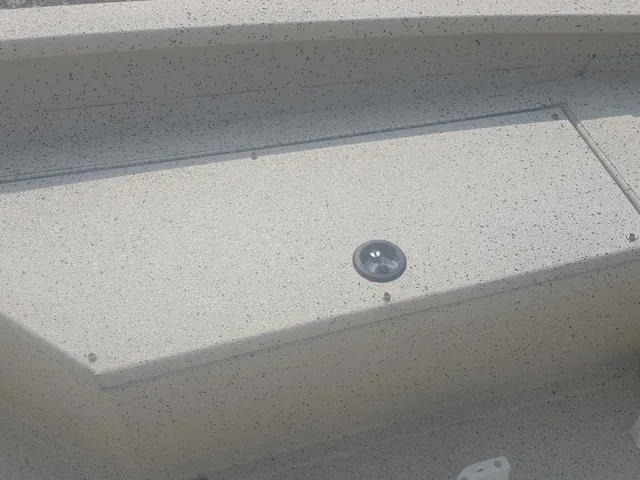 Slide: The Image of A detail of the deck on a 2012 Xpress H22B Bay boat, featuring a round hatch. - 23