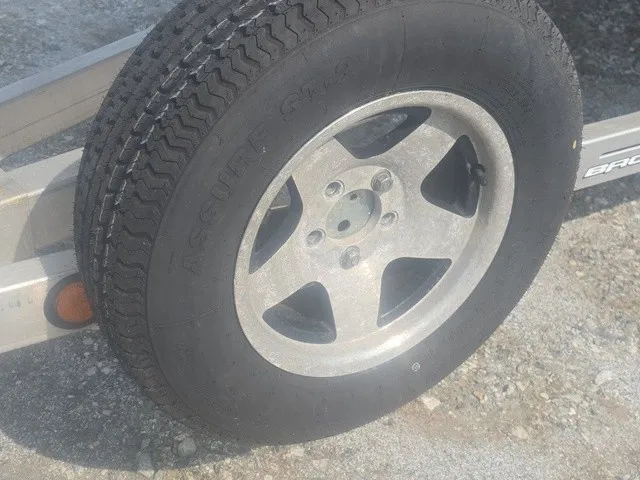 Slide: The Image of Close-up of a boat trailer wheel with a sturdy tire and rim on gravel. - 33