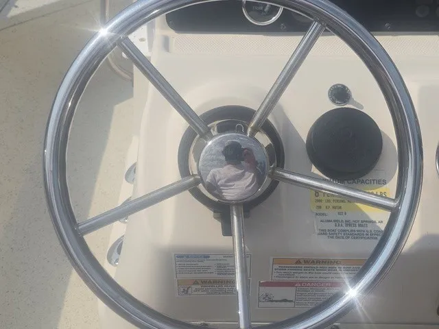 Slide: The Image of The image shows a shiny metal steering wheel on a boat, surrounded by warning labels. - 21
