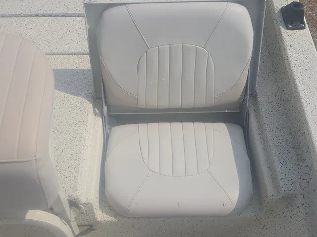 Slide: The Image of A white, cushioned boat seat with vertical stitching on a textured deck. - 27