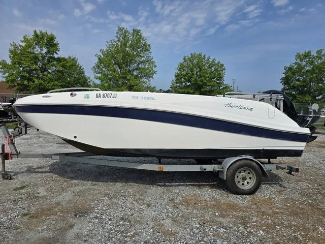 Slide: The Image of A white 2021 Hurricane SunDeck Sport 192 RL OB boat on a trailer in a gravel lot. - 7