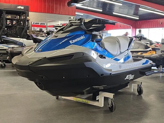Slide: The Image of A blue 2026 Kawasaki Jet Ski STX is displayed in a showroom on a rolling stand. - 2