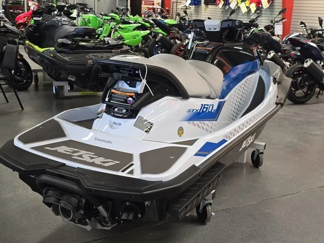 Slide: The Image of A 2026 Kawasaki Jet Ski STX is in a showroom, surrounded by other watercraft. - 5