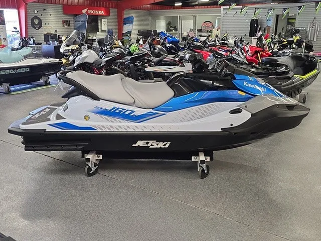 Slide: The Image of A 2026 Kawasaki Jet Ski STX in a showroom, surrounded by other personal watercraft. - 6