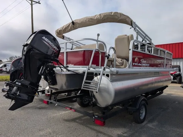 Slide: The Image of A 2025 Sun Tracker Party Barge 18 DLX on a trailer. It features an outboard motor and a sunshade. - 25