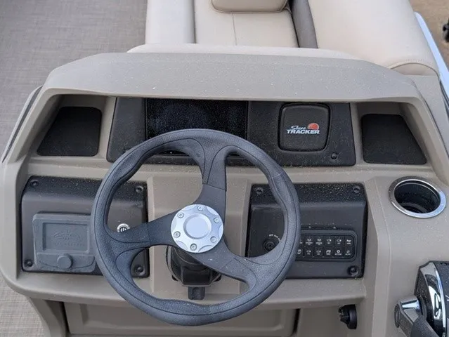 Slide: The Image of The image shows the helm of a Sun Tracker Party Barge 18 DLX pontoon boat with a steering wheel and controls. - 18