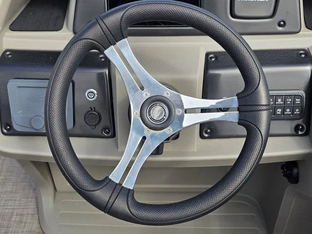 Slide: The Image of The image shows the steering wheel of a 2025 Sun Tracker Fishin' Barge 20 DLX. It features a modern black grip and silver spokes. - 23