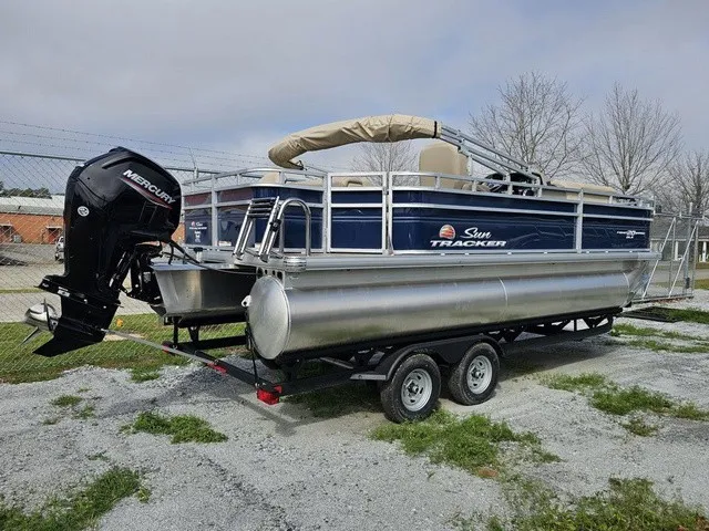 Slide: The Image of A 2025 Sun Tracker Fishin' Barge 20 DLX on a trailer. It features an outboard motor. - 4