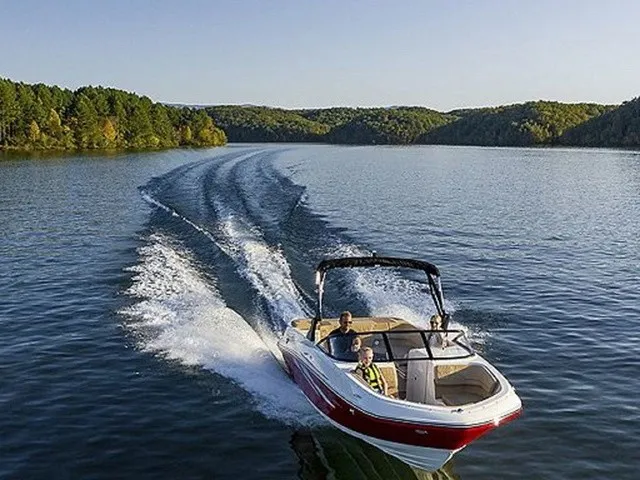 The Image of A 2023 Bayliner VR6 Bowrider cruising on a calm lake, surrounded by wooded hills. - 1