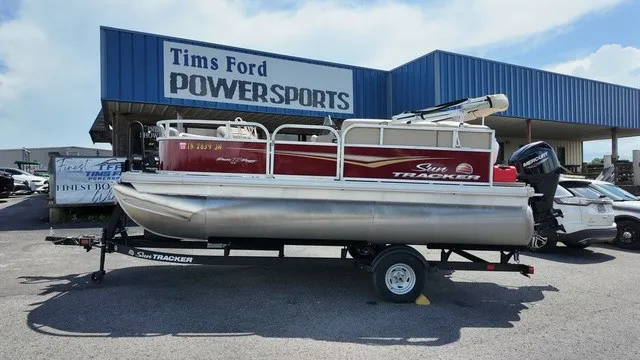 The Image of A Sun Tracker Bass Buggy 16 XL Select pontoon boat on a trailer in front of a store. - 1