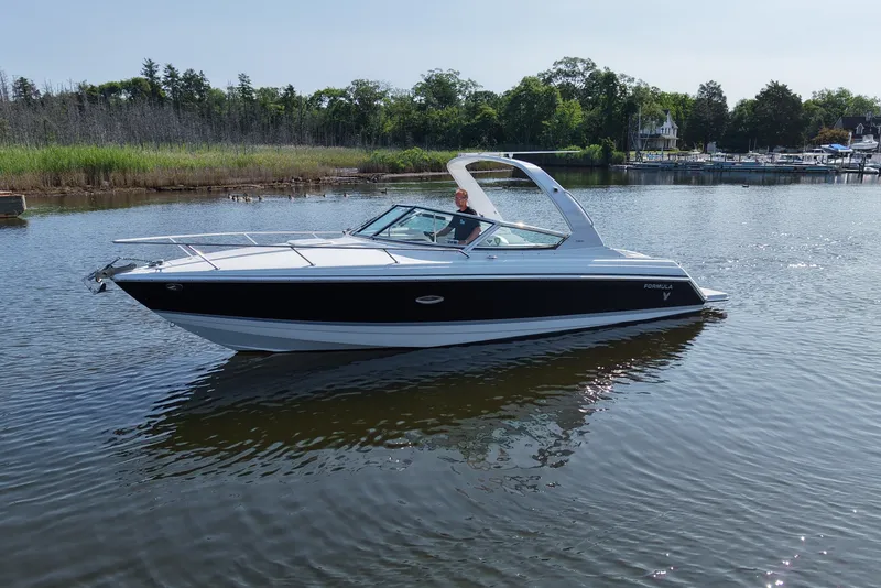 Slide: The Image of A white and black motorboat floating on calm water, surrounded by trees and a marina. - 2