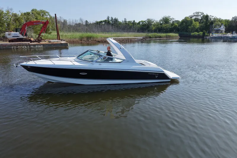 Slide: The Image of Formula 280 Sun Sport boat cruising on a calm river near a dock and greenery. - 1