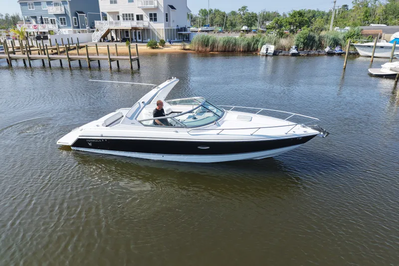 Slide: The Image of A Formula 280 Sun Sport boat cruising on a calm river near residential docks. - 10
