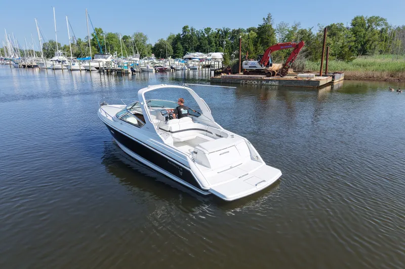 Slide: The Image of Formula 280 Sun Sport boat cruising in a marina with sailboats and trees in the background. - 13