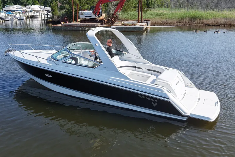 The Image of Formula 280 Sun Sport boat cruising on a calm lake near a marina. - 0