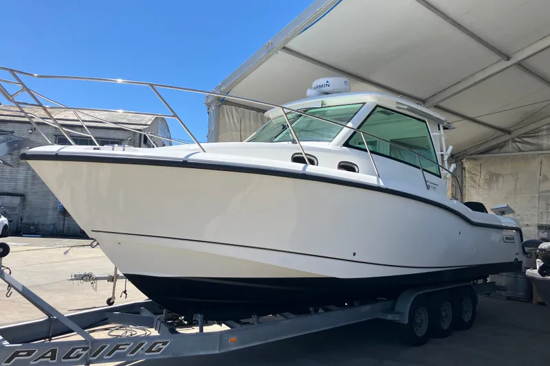 Slide: The Image of 2019 Boston Whaler 315 Conquest Pilothouse on trailer under canopy. - 12