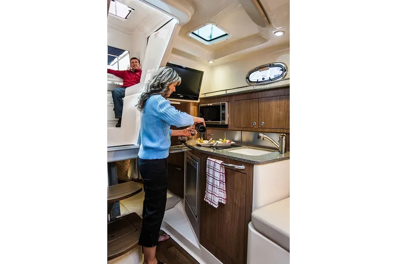 Slide: The Image of Manufacturer Provided Image: 2019 Boston Whaler 315 Conquest Pilothouse interior with people in the kitchen area. - 9