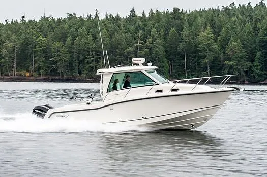 Slide: The Image of Manufacturer Provided Image: 2019 Boston Whaler 315 Conquest Pilothouse cruising on a lake with forested shoreline. - 2