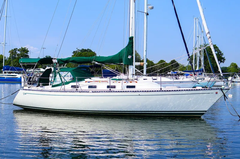 The Image of 1988 Tartan 34-2 sailboat docked in a marina, featuring green sails and calm waters. - 0