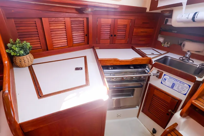Slide: The Image of Compact 1988 Tartan 34-2 yacht kitchen with wooden cabinetry and stainless steel stove. - 33