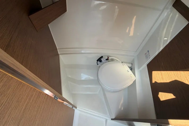 Slide: The Image of Compact bathroom in 2019 Jeanneau NC 695 boat, featuring a modern marine toilet. - 21