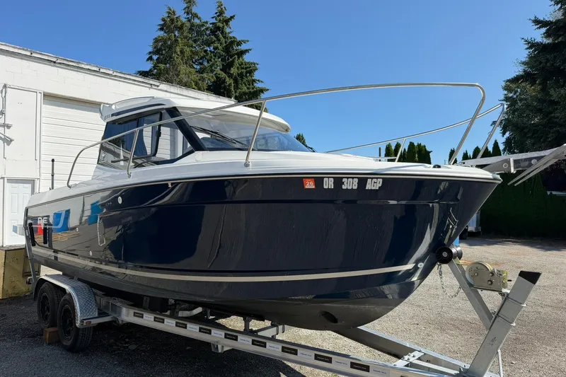 Slide: The Image of 2019 Jeanneau NC 695 boat on trailer, parked outdoors under clear blue sky. - 15