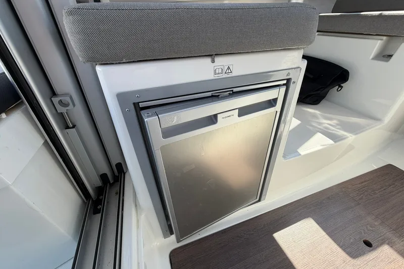 Slide: The Image of Interior of 2019 Jeanneau NC 695 boat featuring a compact Dometic refrigerator. - 20