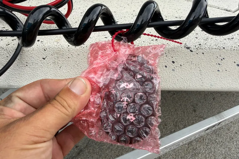 Slide: The Image of Hand holding bubble-wrapped item near black spiral cable on 2016 Xpress H18 Bay boat. - 16