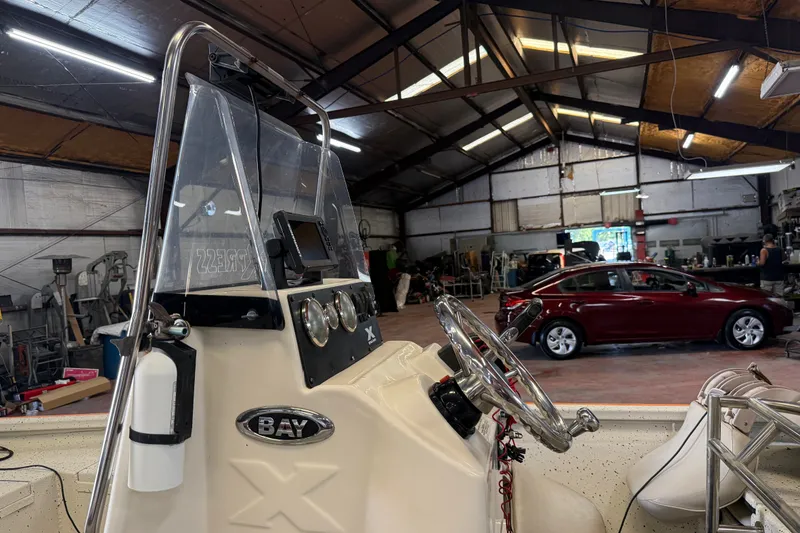 Slide: The Image of 2016 Xpress H18 Bay boat in a workshop with a red car in the background. - 14