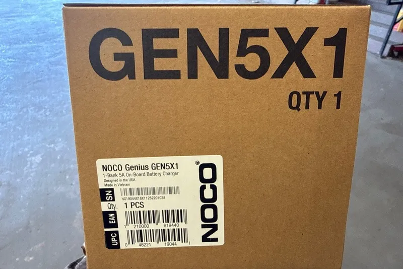 Slide: The Image of Box of NOCO Genius GEN5X1 battery charger, labeled "QTY 1," on a warehouse floor. - 15