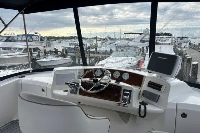 Slide: The Image of 2006 Silverton 34 Convertible helm with marina view, featuring steering wheel and navigation equipment. - 21