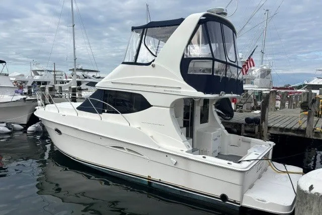 The Image of 2006 Silverton 34 Convertible yacht docked at a marina, featuring a sleek white design. - 0